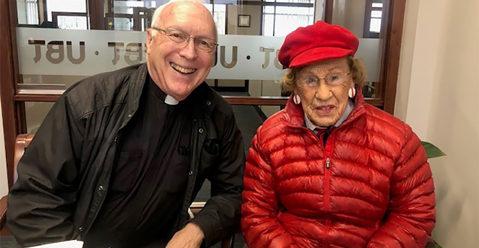 A photo of Helen Witt with a priest