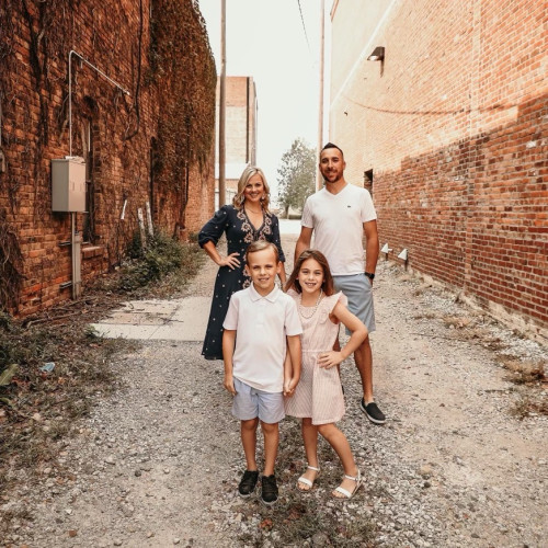 A husband and wife and their two young kids posing in an alley for a family portrait