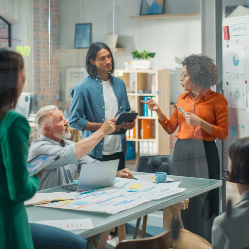 a group of people stand around a table in the office