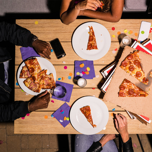 people sit around a table eating pizza