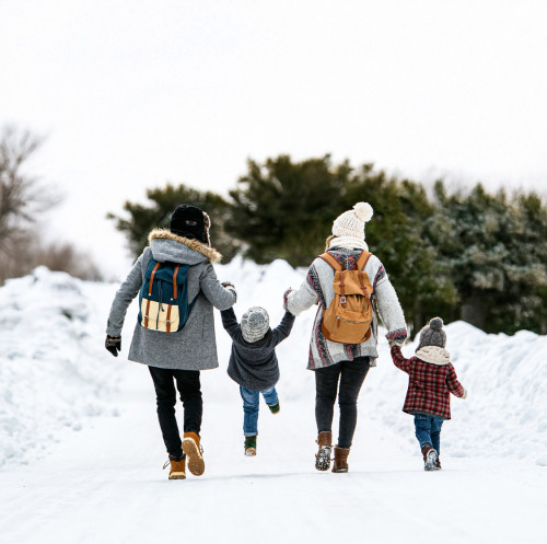 a family plays in the snow with their backs to the camera