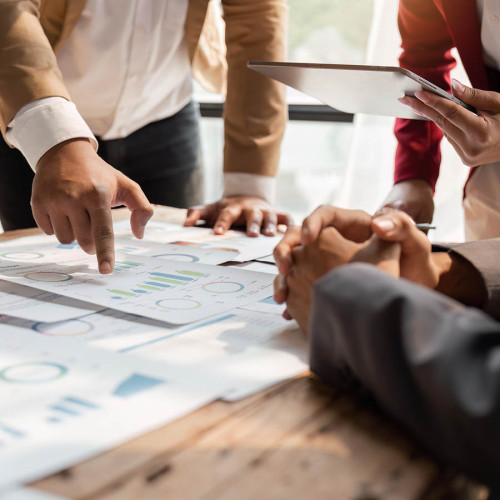 Two sets of hands pointing out things on a paper chart on a table