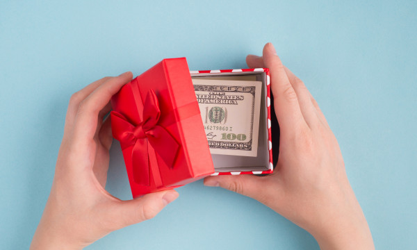 A pair of hands opening a small box with cash inside.