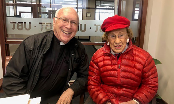 A photo of Helen Witt with a priest
